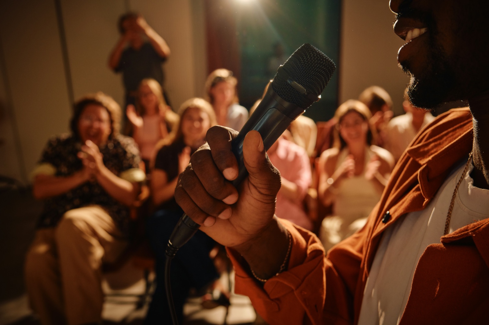 A hand reaching for the microphone in a full room
