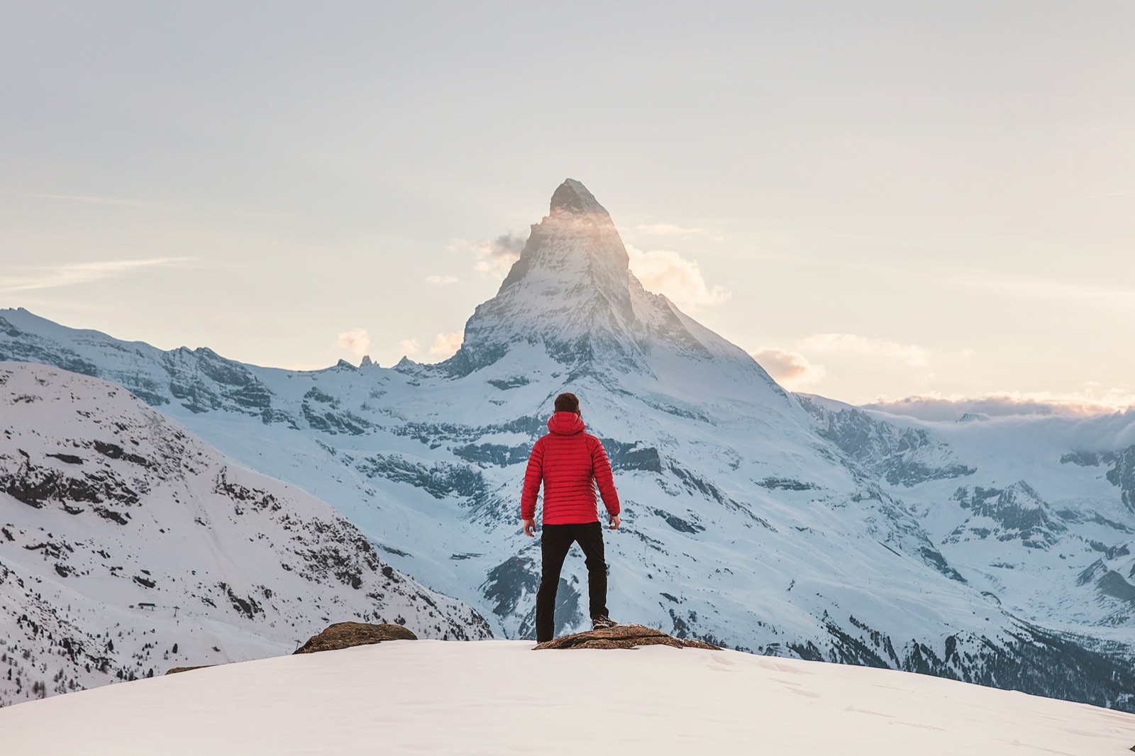 A climber in red on a snowy summit